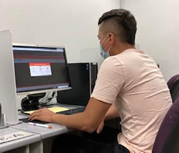 Student sitting in cubicle taking test on computer